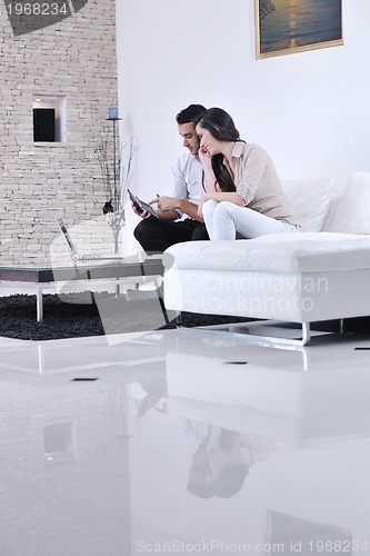 Image of joyful couple relax and work on laptop computer at modern home