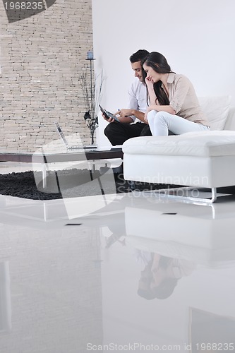 Image of joyful couple relax and work on laptop computer at modern home