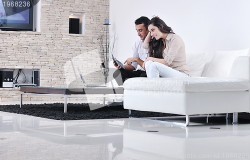 Image of joyful couple relax and work on laptop computer at modern home
