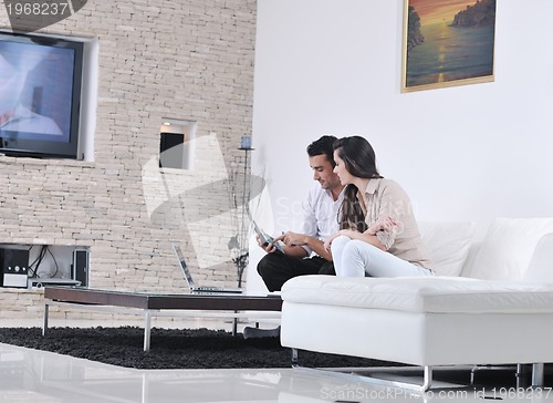 Image of joyful couple relax and work on laptop computer at modern home