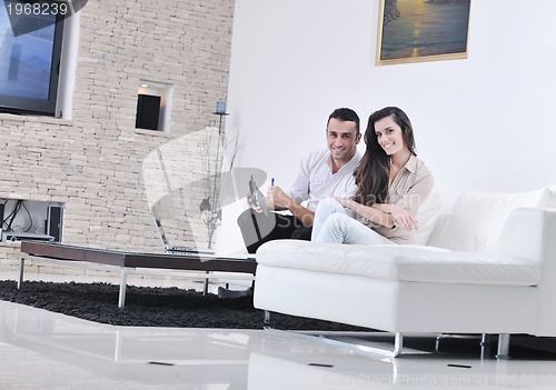 Image of joyful couple relax and work on laptop computer at modern home
