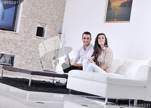 Image of joyful couple relax and work on laptop computer at modern home