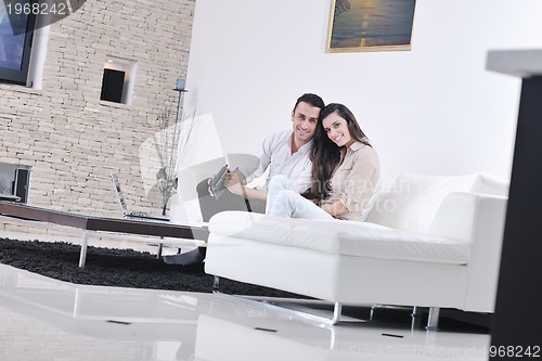 Image of joyful couple relax and work on laptop computer at modern home