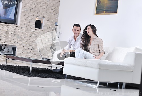 Image of joyful couple relax and work on laptop computer at modern home