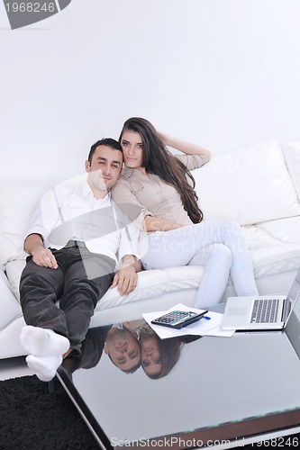 Image of joyful couple relax and work on laptop computer at modern home