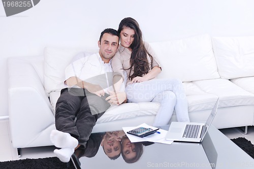 Image of joyful couple relax and work on laptop computer at modern home