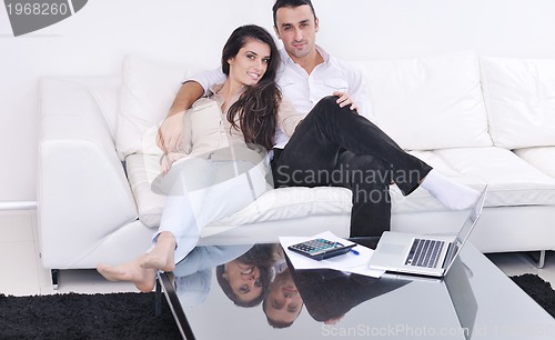 Image of joyful couple relax and work on laptop computer at modern home