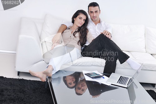 Image of joyful couple relax and work on laptop computer at modern home