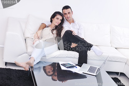 Image of joyful couple relax and work on laptop computer at modern home
