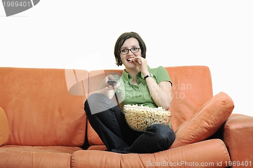 Image of young woman eat popcorn on orange sofa