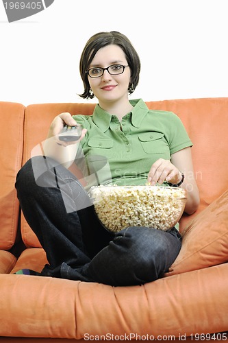 Image of young woman eat popcorn on orange sofa