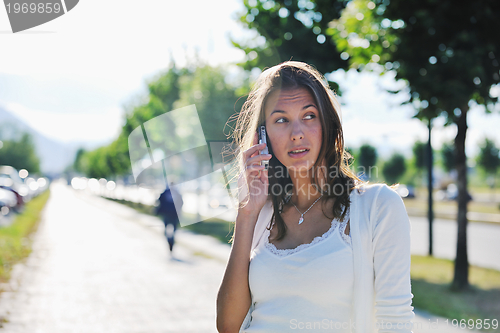 Image of young woman talk by cellphone on street