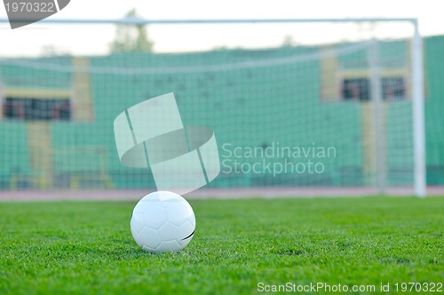 Image of Soccer ball on grass at goal and stadium in background