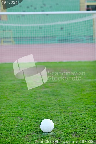 Image of Soccer ball on grass at goal and stadium in background