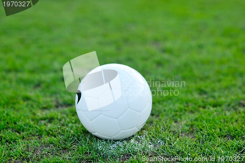 Image of Soccer ball on grass at goal and stadium in background