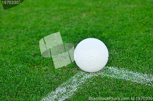 Image of Soccer ball on grass at goal and stadium in background