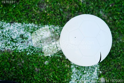 Image of Soccer ball on grass at goal and stadium in background