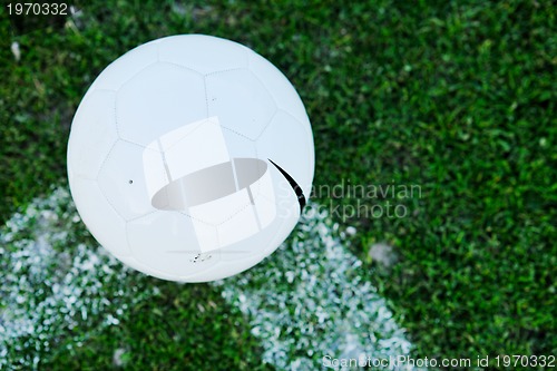 Image of Soccer ball on grass at goal and stadium in background