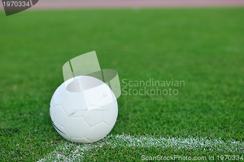 Image of Soccer ball on grass at goal and stadium in background