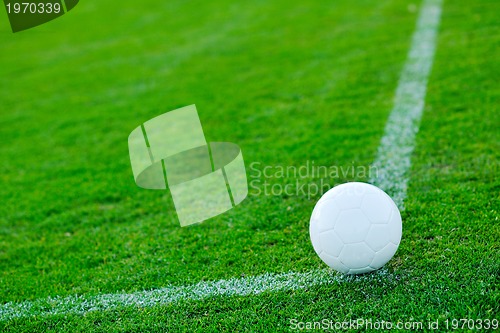 Image of Soccer ball on grass at goal and stadium in background