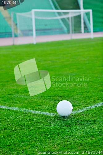 Image of Soccer ball on grass at goal and stadium in background