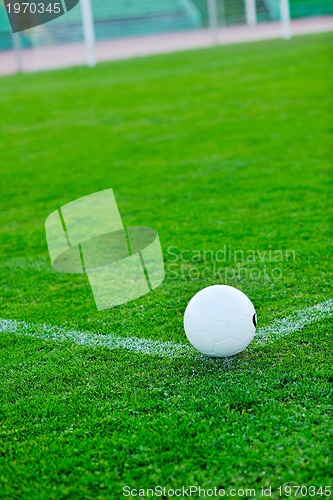 Image of Soccer ball on grass at goal and stadium in background