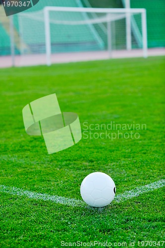 Image of Soccer ball on grass at goal and stadium in background