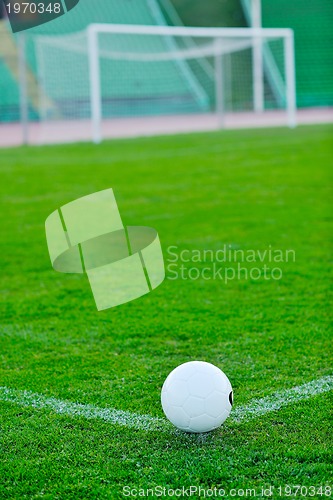 Image of Soccer ball on grass at goal and stadium in background