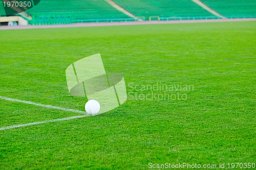 Image of Soccer ball on grass at goal and stadium in background