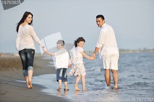 Image of happy young family have fun on beach at sunset