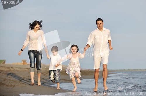 Image of happy young family have fun on beach at sunset