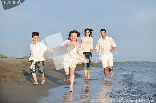 Image of happy young family have fun on beach at sunset