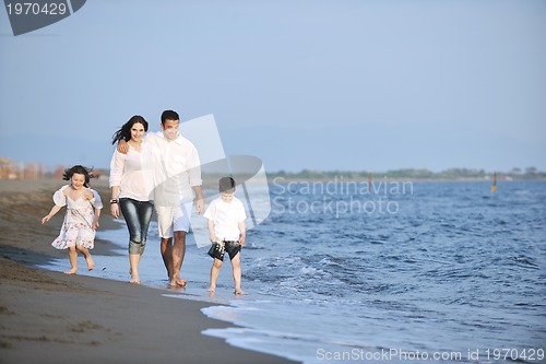 Image of happy young family have fun on beach at sunset