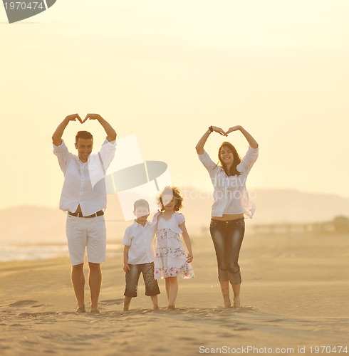 Image of happy young family have fun on beach at sunset