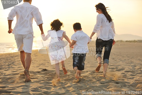 Image of happy young family have fun on beach at sunset