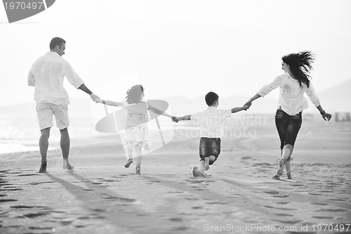 Image of happy young family have fun on beach at sunset