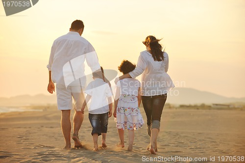Image of happy young family have fun on beach at sunset