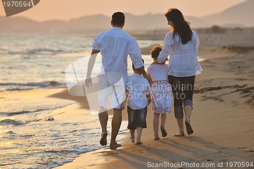 Image of happy young family have fun on beach at sunset