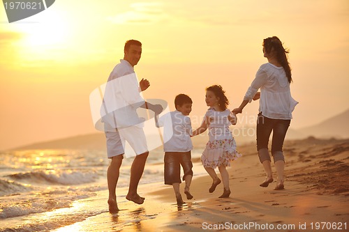 Image of happy young family have fun on beach at sunset