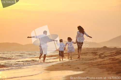 Image of happy young family have fun on beach at sunset
