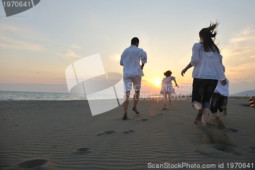 Image of happy young family have fun on beach at sunset