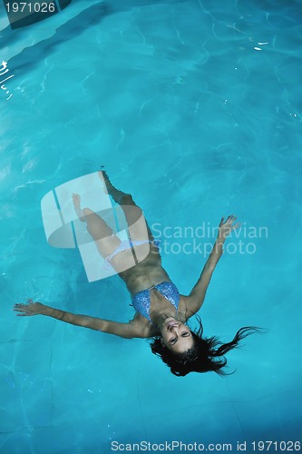 Image of pretty young lady  relaxing in the swimming pool