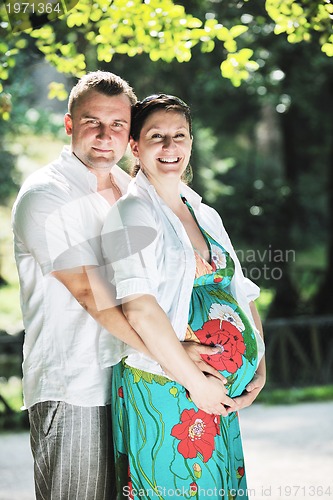 Image of Happy pregnant couple at beautiful sunny day in park