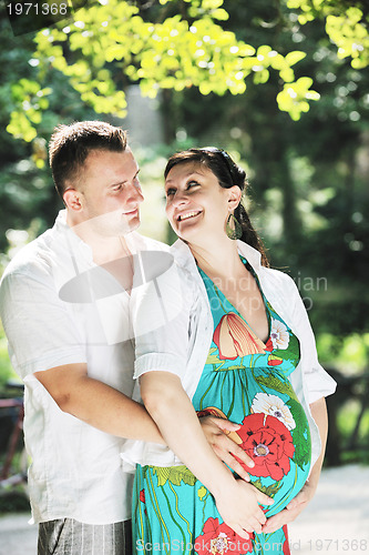 Image of Happy pregnant couple at beautiful sunny day in park