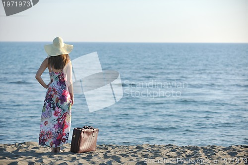 Image of woman with suitcase on the beach