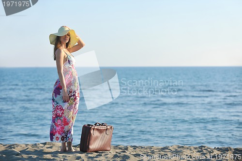 Image of woman with suitcase on the beach