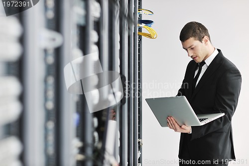 Image of businessman with laptop in network server room