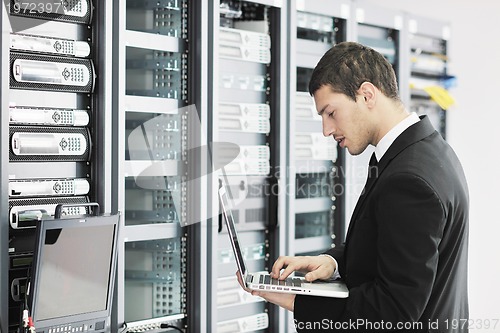 Image of businessman with laptop in network server room