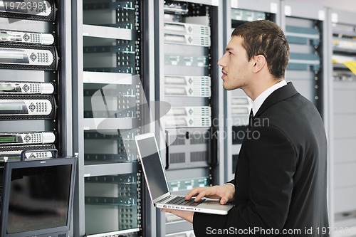 Image of businessman with laptop in network server room