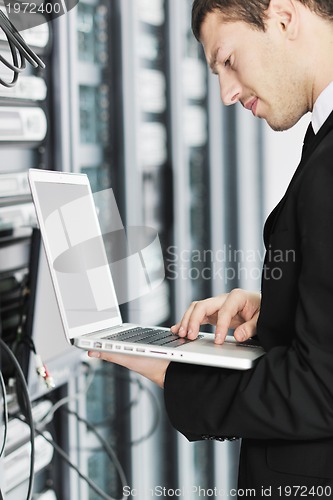 Image of businessman with laptop in network server room